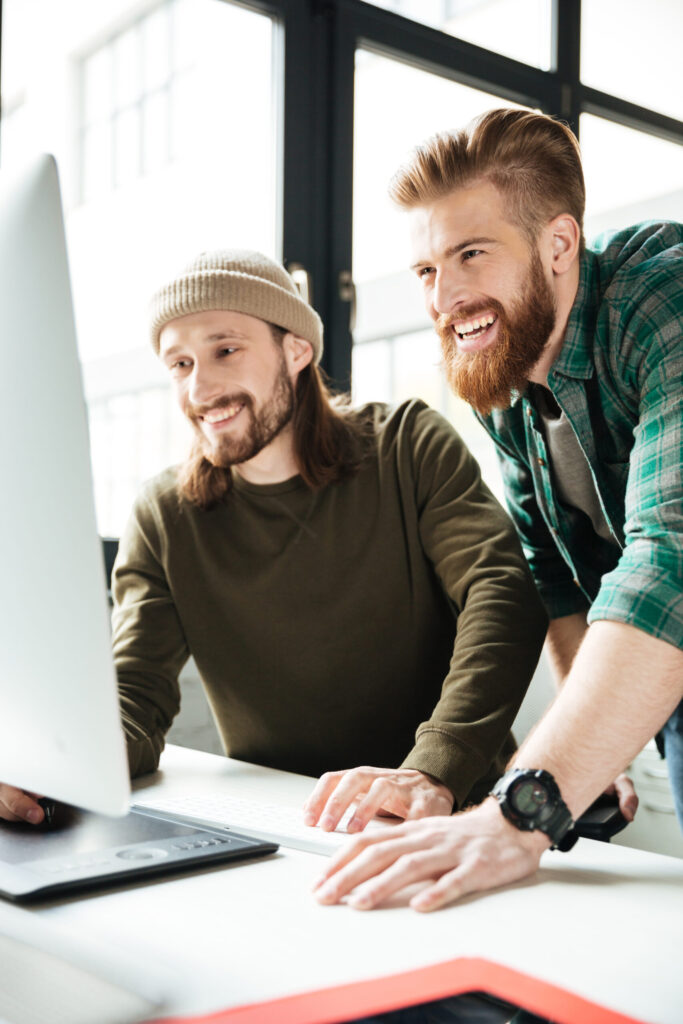 Zwei Männer freuen sich am Computer über Webdesign